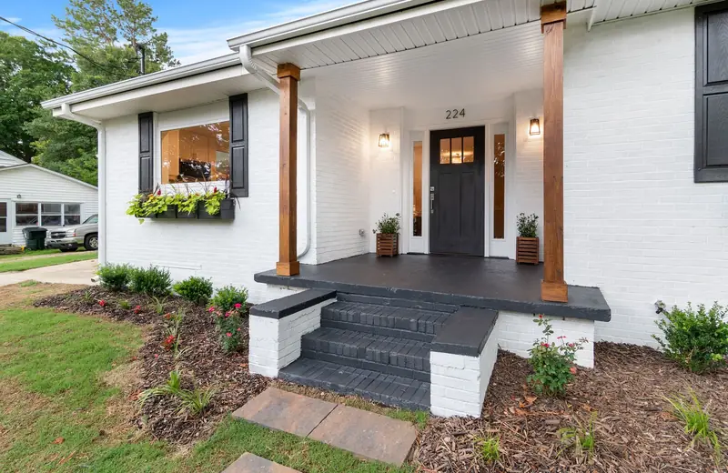 Front porch of a white brick house with wood columns